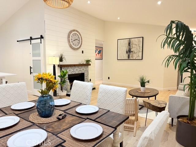 1254 W Van Koevering St, Rialto, CA 92376 - dining room with a barn door, recessed lighting, a tile fireplace, high vaulted ceiling, and light wood-style flooring