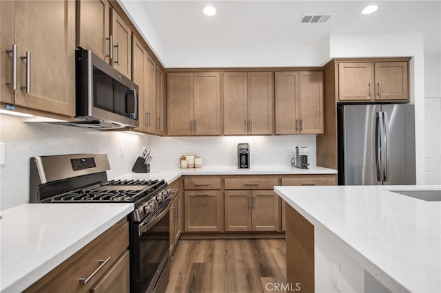 39376 Corvina Ln, Temecula, CA 92591 - kitchen featuring appliances with stainless steel finishes, light countertops, dark wood finished floors, recessed lighting, and brown cabinetry