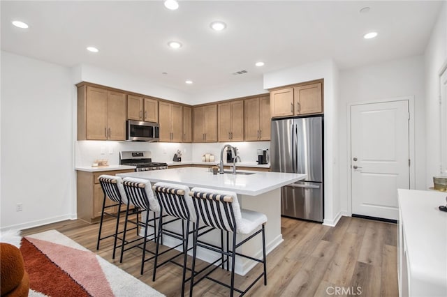 39376 Corvina Ln, Temecula, CA 92591 - kitchen featuring appliances with stainless steel finishes, a sink, an island with sink, a kitchen breakfast bar, and light countertops
