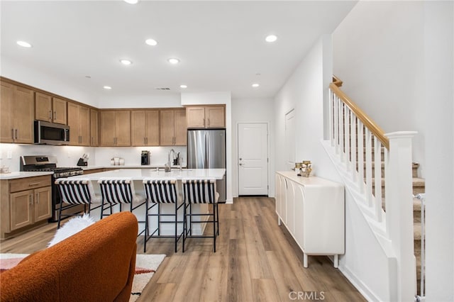 39376 Corvina Ln, Temecula, CA 92591 - kitchen with stainless steel appliances, light countertops, light wood-type flooring, recessed lighting, and a kitchen bar