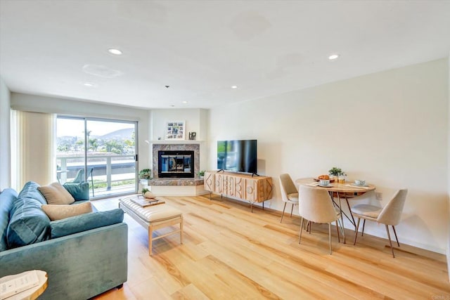 1616 Circa Del Lago Unit C206, San Marcos, CA 92078 - living area featuring light wood finished floors, recessed lighting, a glass covered fireplace, and baseboards