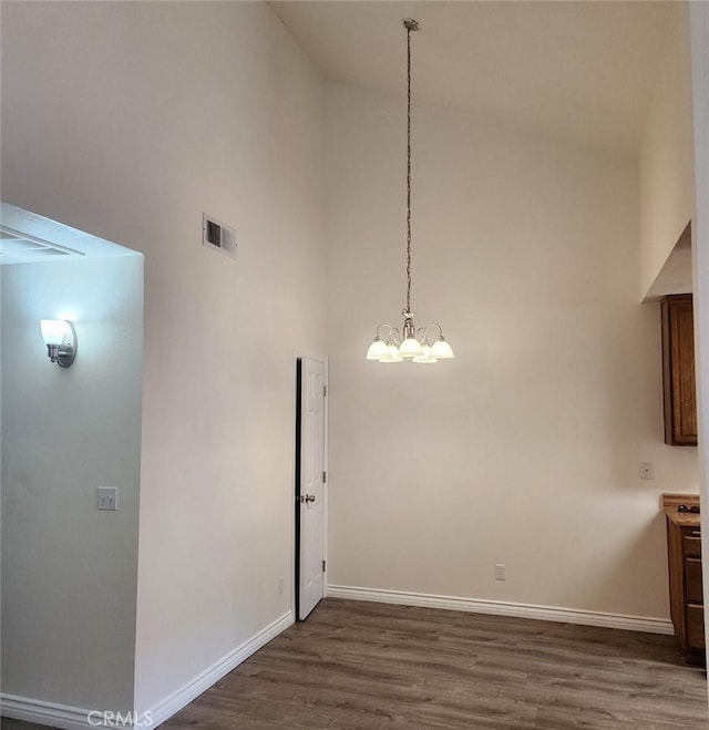 27971 Sarabande Ln Unit 230, Canyon Country, CA 91387 - unfurnished dining area featuring high vaulted ceiling, dark wood-style flooring, and a chandelier