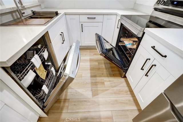 23391 Park Sorrento Unit 62, Calabasas, CA 91302 - kitchen featuring stainless steel range with electric stovetop, light wood-type flooring, white cabinetry, light countertops, and a sink