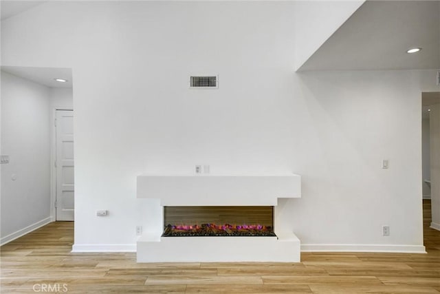 23391 Park Sorrento Unit 62, Calabasas, CA 91302 - unfurnished living room with a warm lit fireplace, baseboards, wood finished floors, and recessed lighting