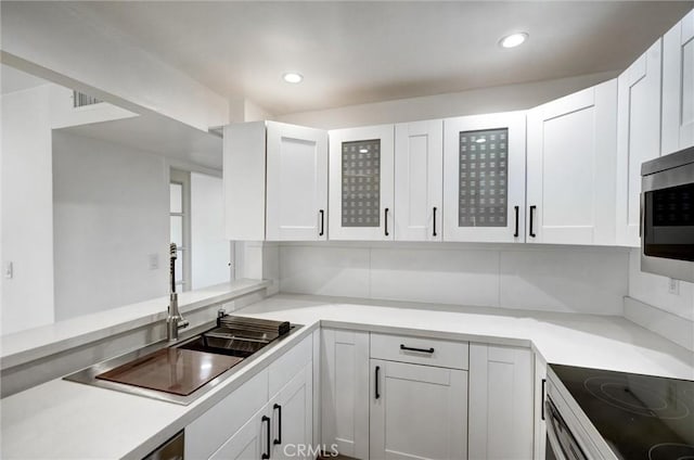 23391 Park Sorrento Unit 62, Calabasas, CA 91302 - kitchen featuring stainless steel microwave, white cabinetry, glass insert cabinets, light countertops, and a sink