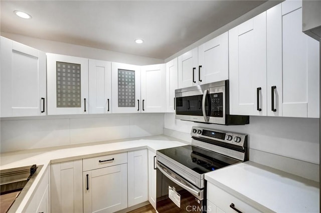 23391 Park Sorrento Unit 62, Calabasas, CA 91302 - kitchen with stainless steel appliances, white cabinets, light countertops, glass insert cabinets, and recessed lighting
