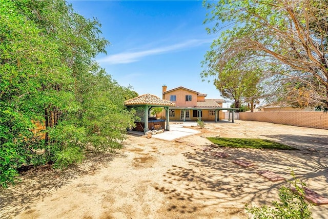 3065 Sabre St, Rosamond, CA 93560 - rear view of house with a hot tub, a gazebo, a patio, a tile roof, and a chimney