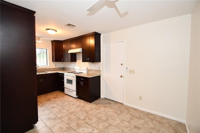 1069 Donahue St, San Diego, CA 92110 - kitchen with white gas range oven, ceiling fan, under cabinet range hood, dark brown cabinetry, and light stone countertops