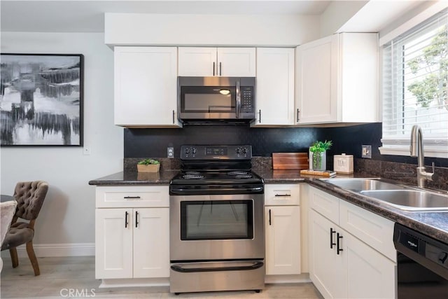 19847 Coventry Ln, Huntington Beach, CA 92646 - kitchen with appliances with stainless steel finishes, white cabinetry, dark stone counters, and light wood-style flooring