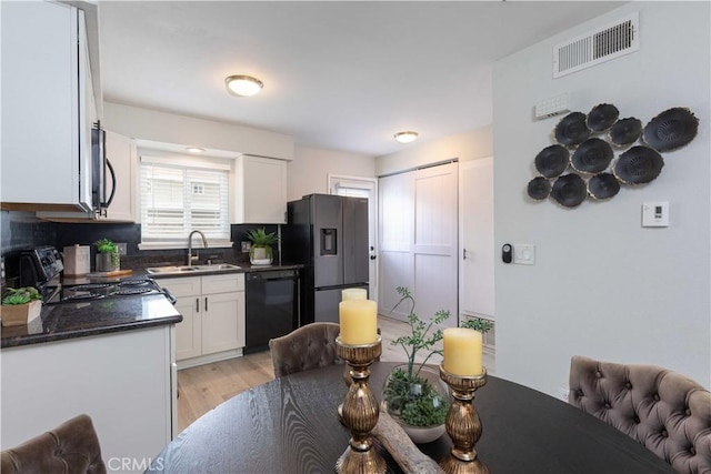 19847 Coventry Ln, Huntington Beach, CA 92646 - kitchen with black appliances, dark countertops, white cabinets, light wood-type flooring, and tasteful backsplash