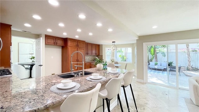 4 Salerno, Irvine, CA 92614 - kitchen with brown cabinets, recessed lighting, light stone countertops, a peninsula, and stainless steel gas stovetop