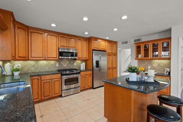 21905 Grovepark Dr, Saugus, CA 91350 - kitchen with stainless steel appliances, a sink, backsplash, brown cabinets, and glass insert cabinets