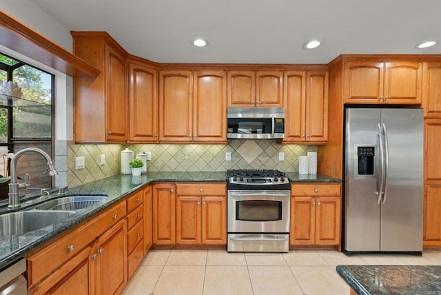 21905 Grovepark Dr, Saugus, CA 91350 - kitchen featuring appliances with stainless steel finishes, a sink, dark stone counters, brown cabinetry, and recessed lighting