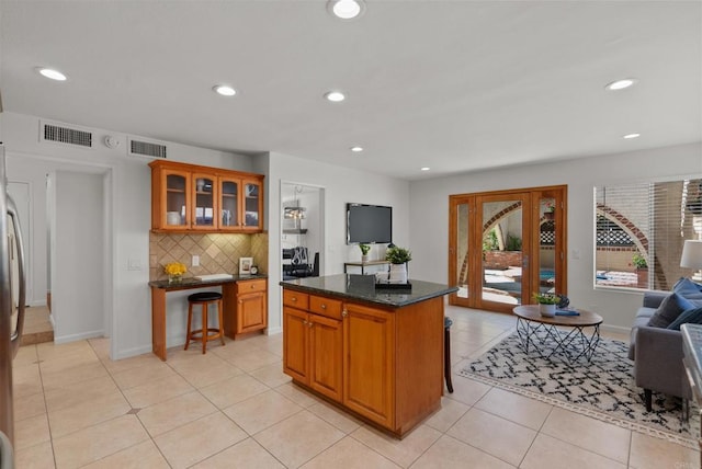 21905 Grovepark Dr, Saugus, CA 91350 - kitchen featuring decorative backsplash, glass insert cabinets, recessed lighting, light tile patterned floors, and brown cabinets