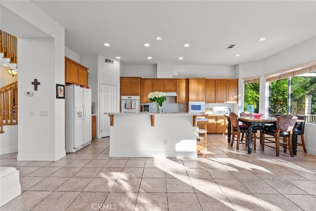 22440 Skylake Pl, Saugus, CA 91390 - kitchen featuring white appliances, light countertops, recessed lighting, a center island, and a breakfast bar area