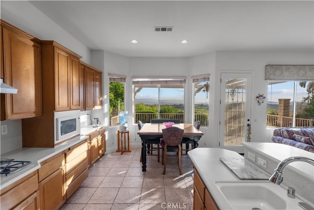 22440 Skylake Pl, Saugus, CA 91390 - kitchen featuring white microwave, light countertops, recessed lighting, brown cabinets, and gas stovetop