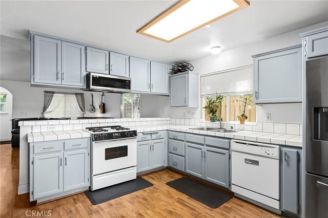 258 Vail Dr, Chico, CA 95973 - kitchen with stainless steel appliances, a sink, tile counters, a peninsula, and healthy amount of natural light