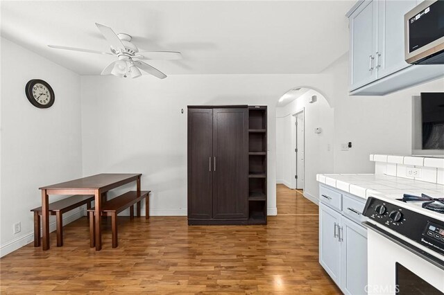 258 Vail Dr, Chico, CA 95973 - kitchen featuring white gas range, open shelves, stainless steel microwave, arched walkways, and tile countertops