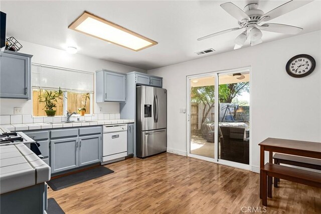 258 Vail Dr, Chico, CA 95973 - kitchen featuring dishwasher, stainless steel fridge, tile countertops, a sink, and light wood-type flooring