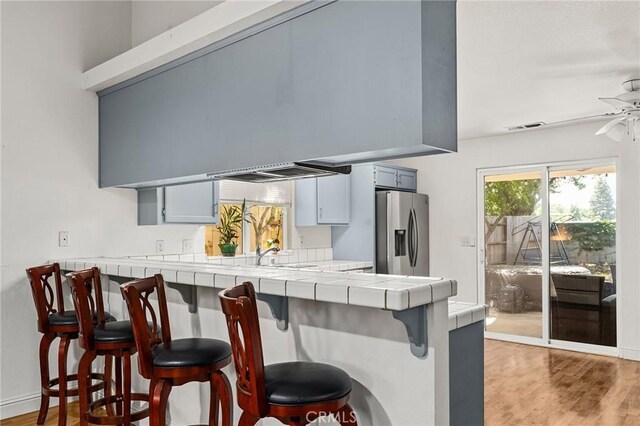 258 Vail Dr, Chico, CA 95973 - kitchen featuring tile countertops, stainless steel fridge with ice dispenser, a breakfast bar area, light wood-type flooring, and ceiling fan