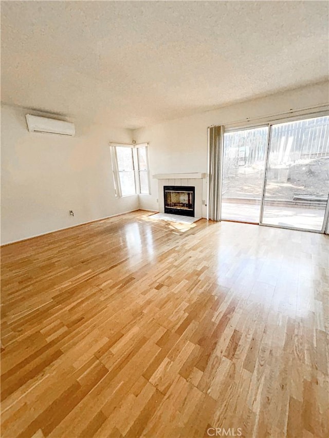 23878 Bouquet Canyon Pl, Moreno Valley, CA 92557 - unfurnished living room featuring light wood finished floors, an AC wall unit, a tile fireplace, and a textured ceiling