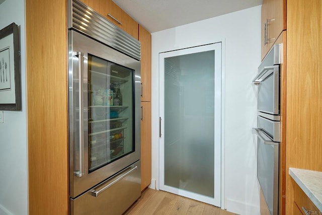 325 7th Unit 1501, San Diego, CA 92101 - kitchen with built in refrigerator, brown cabinetry, light wood finished floors, light countertops, and modern cabinets