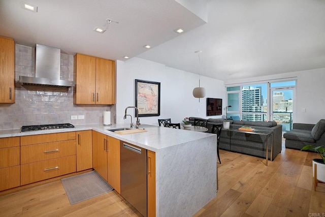 325 7th Unit 1501, San Diego, CA 92101 - kitchen featuring wall chimney exhaust hood, a sink, appliances with stainless steel finishes, a peninsula, and light wood-type flooring