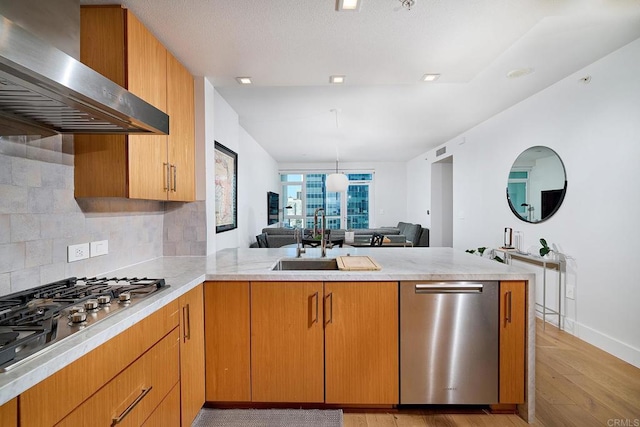 325 7th Unit 1501, San Diego, CA 92101 - kitchen featuring appliances with stainless steel finishes, wall chimney exhaust hood, a sink, a peninsula, and light wood-style flooring