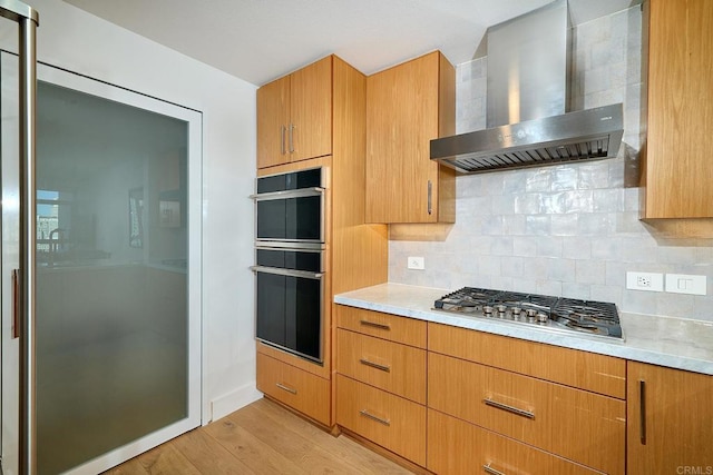 325 7th Unit 1501, San Diego, CA 92101 - kitchen with wall chimney exhaust hood, stainless steel gas cooktop, light countertops, light wood-style flooring, and decorative backsplash