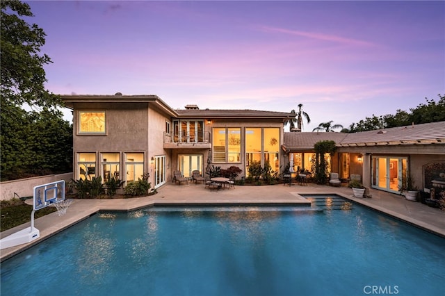 8790 King Ranch Rd, Rancho Cucamonga, CA 91701 - back of house at dusk featuring french doors, a patio, an outdoor pool, and a balcony