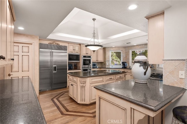 8790 King Ranch Rd, Rancho Cucamonga, CA 91701 - kitchen featuring built in appliances, a raised ceiling, cream cabinets, decorative backsplash, and decorative light fixtures