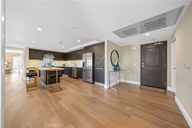 2939 Leeward Ave Unit 415, Los Angeles, CA 90005 - kitchen featuring stainless steel appliances, dark brown cabinetry, light countertops, a breakfast bar, and recessed lighting