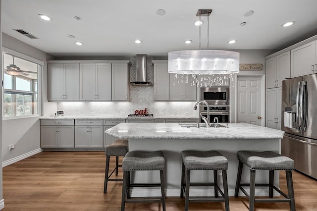1139 Prussian, Oceanside, CA 92057 - kitchen with appliances with stainless steel finishes, wall chimney exhaust hood, a kitchen bar, backsplash, and an island with sink