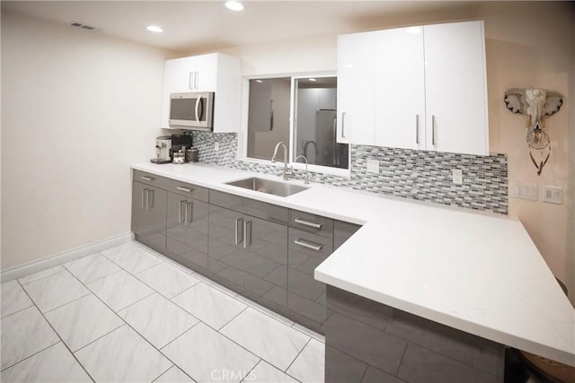 136541/2 Dronfield Ave, Sylmar, CA 91342 - kitchen featuring a sink, stainless steel microwave, gray cabinetry, light countertops, and tasteful backsplash