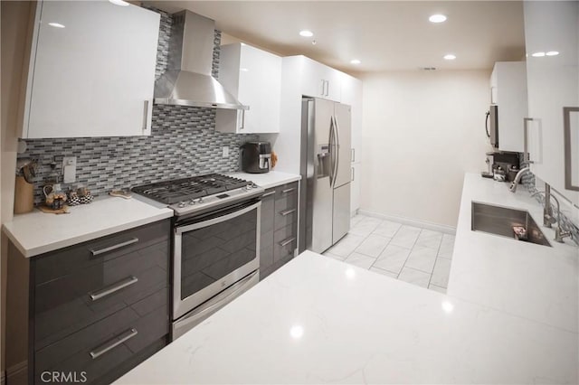 136541/2 Dronfield Ave, Sylmar, CA 91342 - kitchen featuring stainless steel appliances, wall chimney range hood, a sink, tasteful backsplash, and baseboards