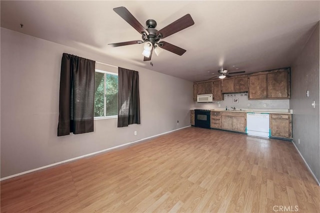 12410 Lakeview Dr, Clearlake Oaks, CA 95423 - unfurnished living room featuring light wood finished floors, a ceiling fan, baseboards, and a sink