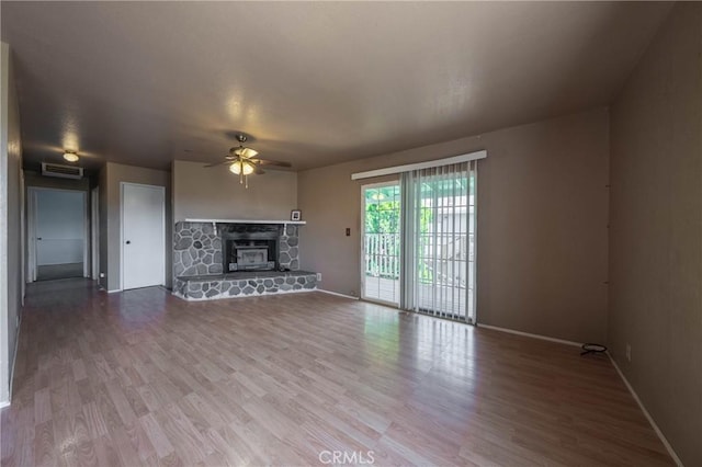 12410 Lakeview Dr, Clearlake Oaks, CA 95423 - unfurnished living room featuring a ceiling fan, baseboards, a stone fireplace, and wood finished floors