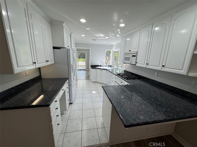 26433 Emerald Dove Dr, Valencia, CA 91355 - kitchen with white appliances, a peninsula, white cabinetry, ornamental molding, and dark stone counters