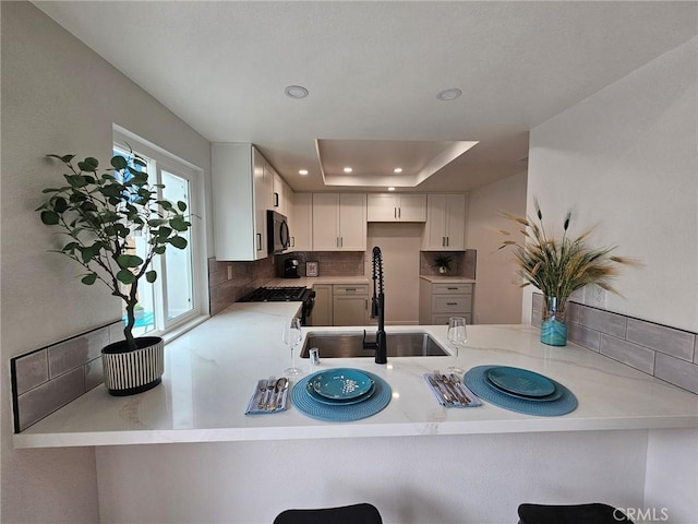 317 Pennyroyal Way, Oceanside, CA 92057 - kitchen featuring a peninsula, backsplash, recessed lighting, a tray ceiling, and white cabinetry