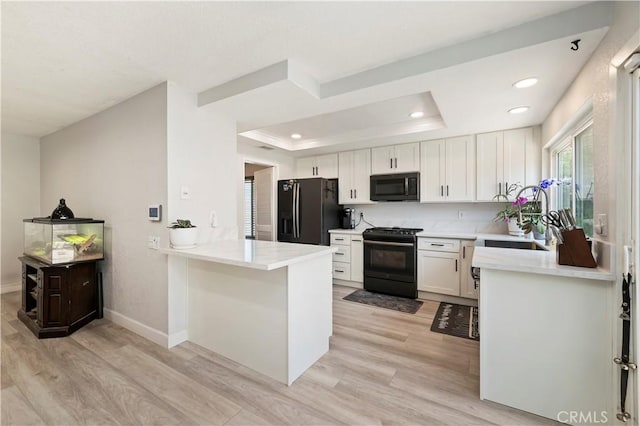 5996 Winncliff Dr, Jurupa Valley, CA 92509 - kitchen featuring black appliances, a sink, light wood-style flooring, a peninsula, and white cabinets