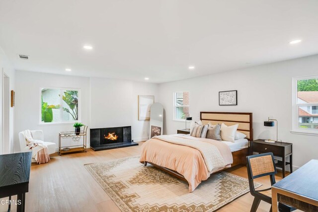 12938 Guadalajara Cir, Cerritos, CA 90703 - bedroom with light wood-style flooring, recessed lighting, a multi sided fireplace, and baseboards