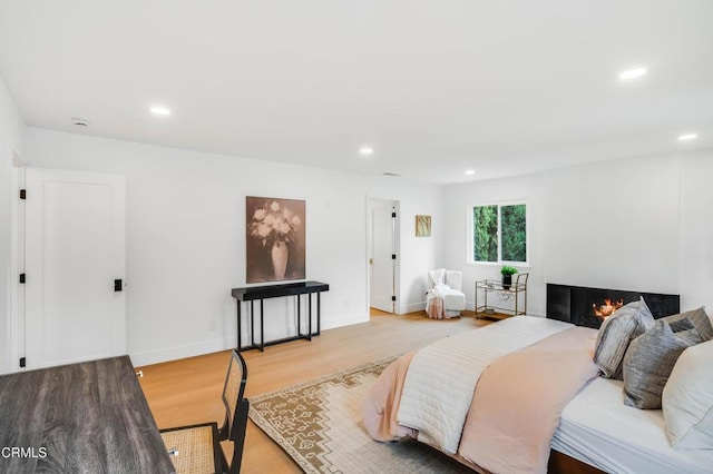 12938 Guadalajara Cir, Cerritos, CA 90703 - bedroom with light wood-type flooring, recessed lighting, a warm lit fireplace, and baseboards