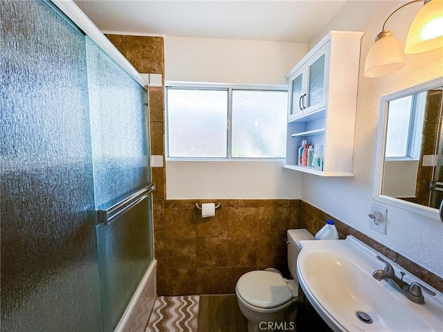45439 Lorimer Ave, Lancaster, CA 93534 - full bathroom with tile walls, toilet, vanity, shower / bath combination with glass door, and a wainscoted wall