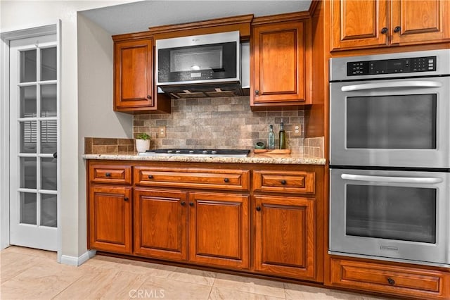 2074 Redgrove Way, Upland, CA 91784 - kitchen featuring appliances with stainless steel finishes, brown cabinets, decorative backsplash, and light stone countertops