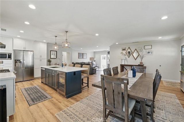 3848 Ocana Ave, Long Beach, CA 90808 - kitchen featuring stainless steel appliances, light countertops, light wood-style floors, white cabinetry, and a kitchen island with sink