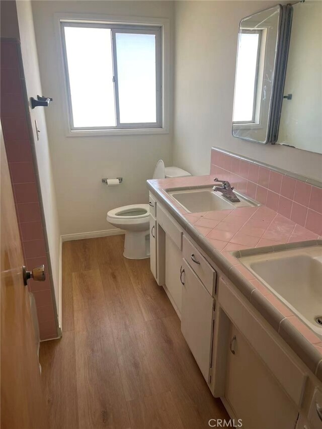 7411 Joshua Ln, Yucca Valley, CA 92284 - full bathroom with wood finished floors, toilet, double vanity, and baseboards