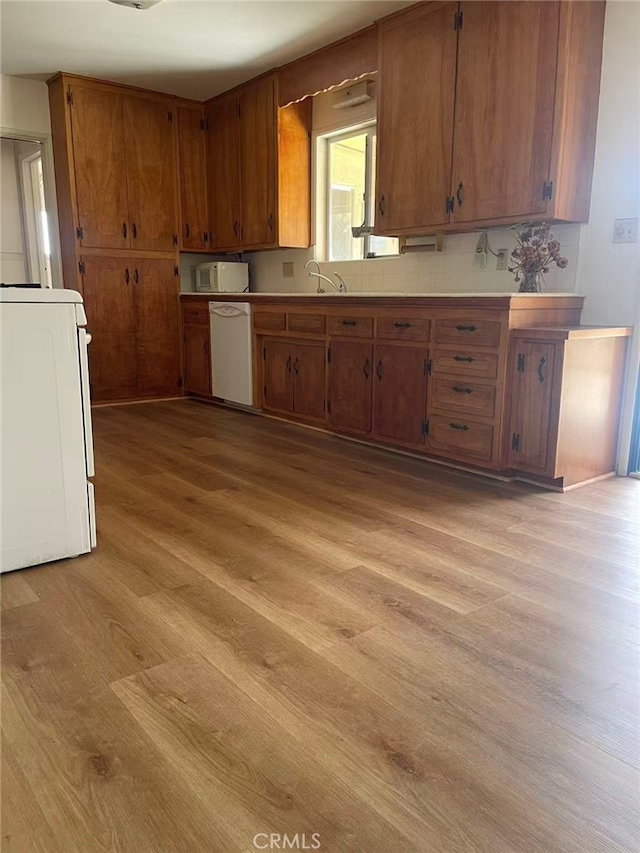 7411 Joshua Ln, Yucca Valley, CA 92284 - kitchen featuring white dishwasher, light wood-style flooring, washer / clothes dryer, brown cabinets, and a sink