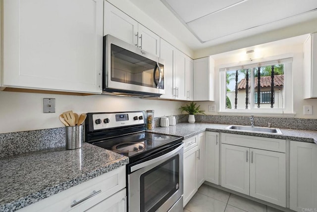 12234 Rancho Bernardo Rd Unit A, Rancho Bernardo San Diego, CA 92128 - kitchen featuring stainless steel appliances, a sink, white cabinets, light tile patterned floors, and dark stone counters