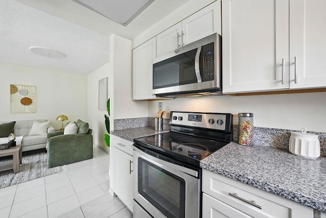 12234 Rancho Bernardo Rd Unit A, Rancho Bernardo San Diego, CA 92128 - kitchen featuring appliances with stainless steel finishes, white cabinets, light stone countertops, light tile patterned floors, and open floor plan
