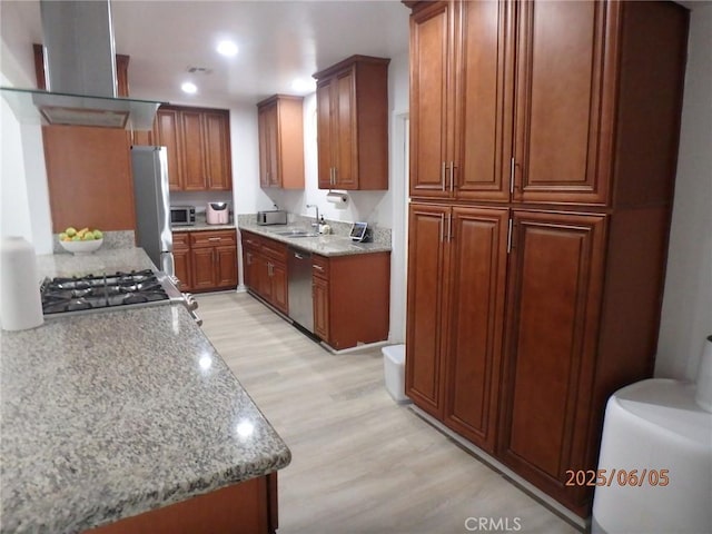 17457 Covello St, Van Nuys, CA 91406 - kitchen featuring island exhaust hood, light wood-style floors, brown cabinetry, a sink, and appliances with stainless steel finishes
